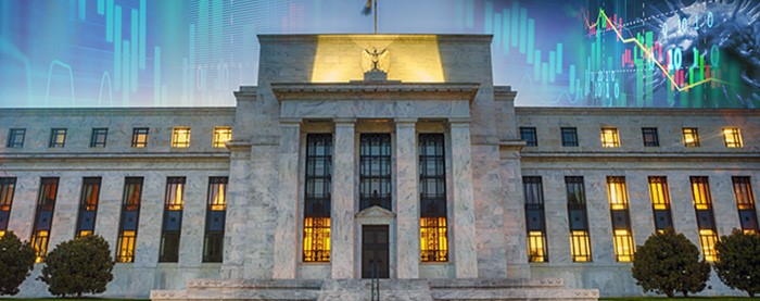 An image of the Federal Reserve Building with stock market ticks in the sky.