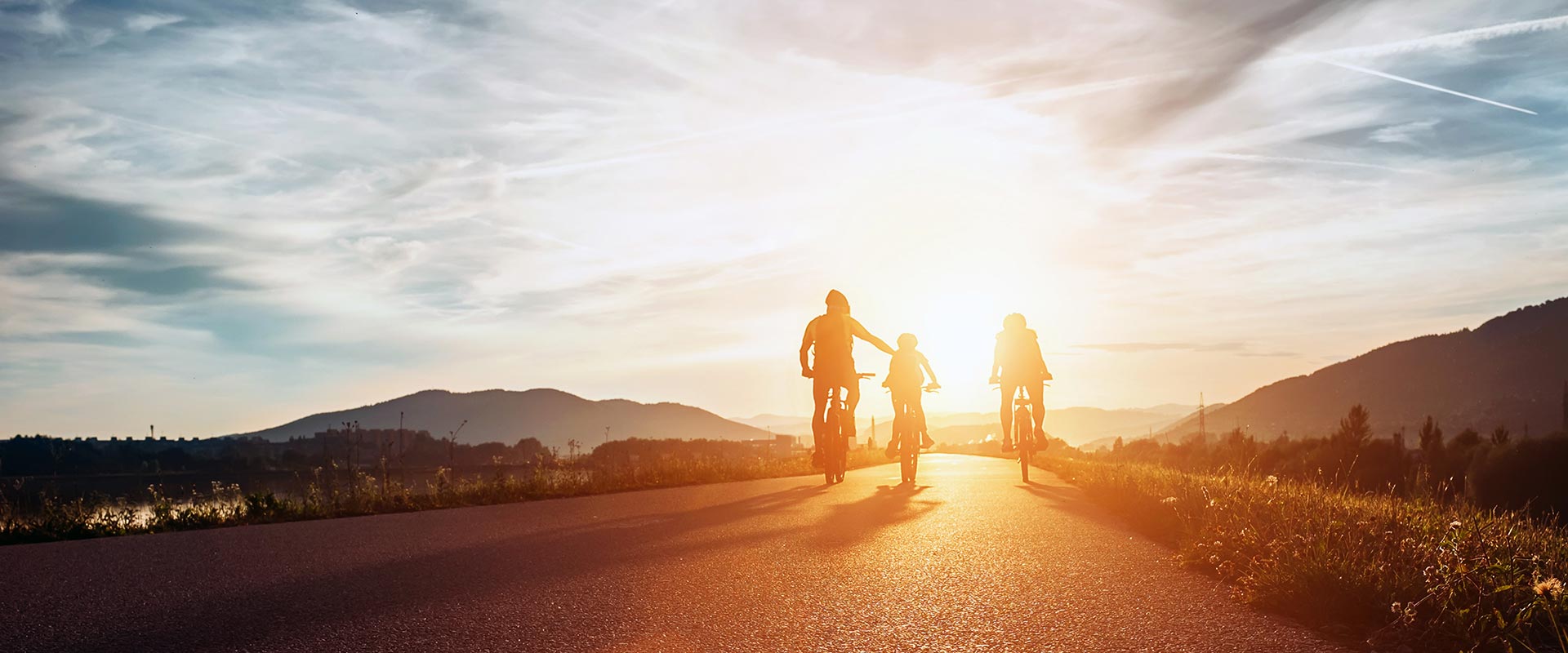 A family riding bikes together at sunset