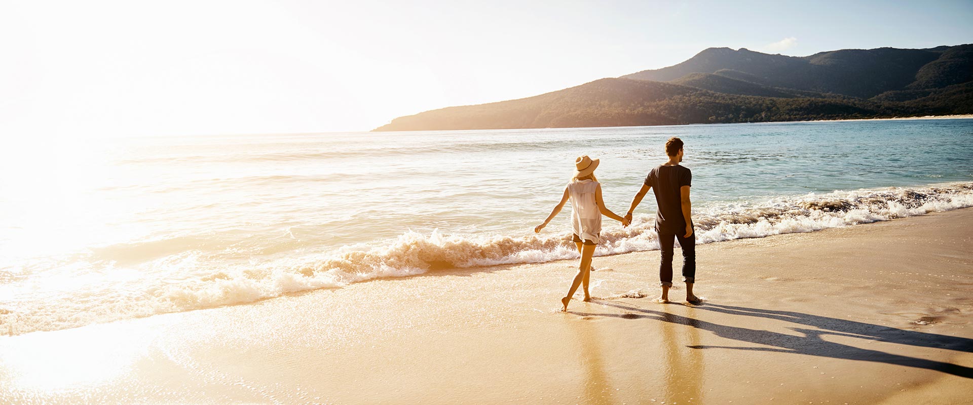 A couple walking along the beach at sunset