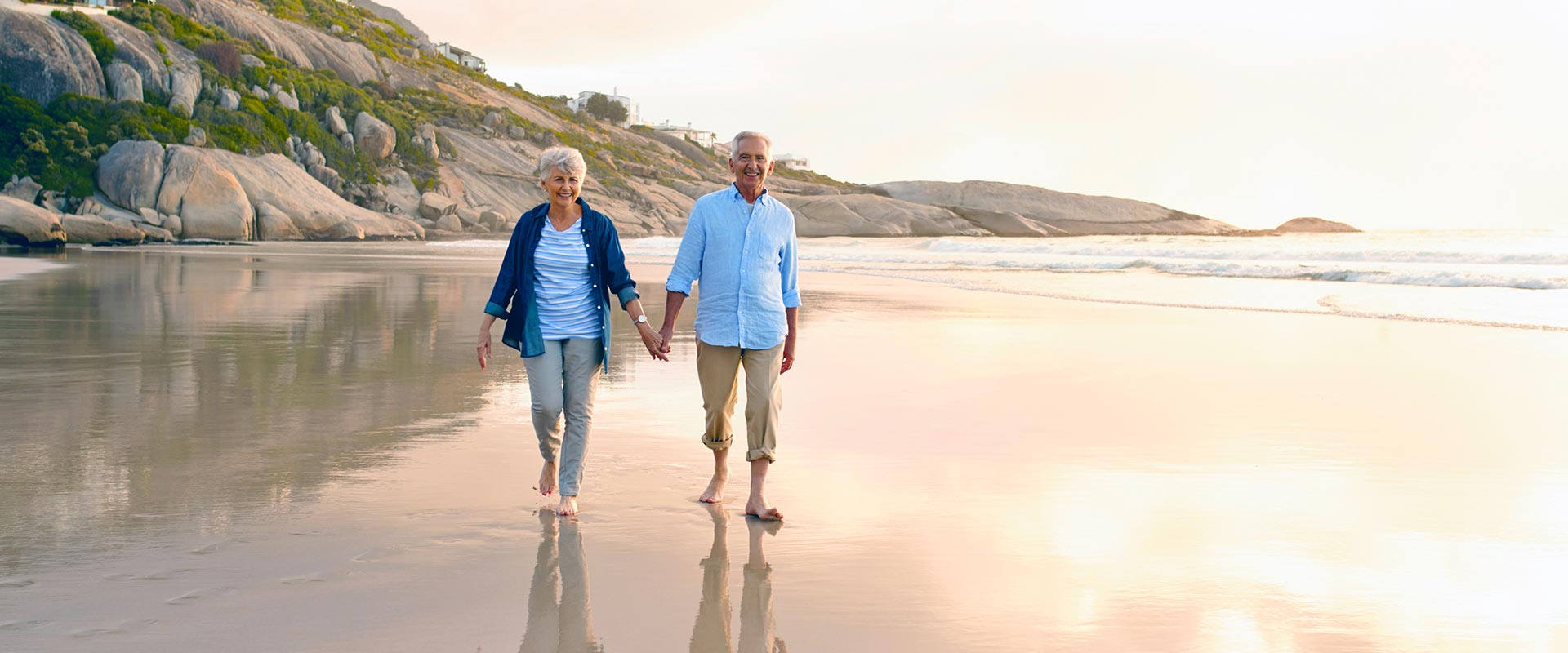 An older couple walking together on the beach