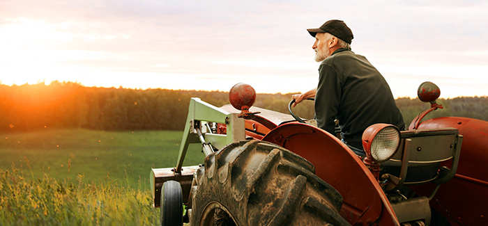 Image of an older farmer on a tractor looking at his farm
