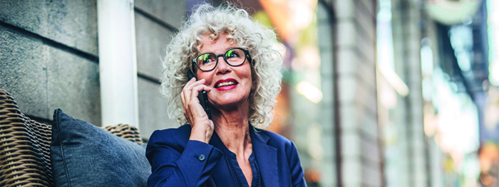 Female Social Security recipient on a business call. Full retirement age based on birth year: 1943–1954 is 66, 1955 is 66 and 2 months, 1956 is 66 and 4 months, 1957 is 66 and 6 months, 1958 is 66 and 8 months, 1959 is 66 and 10 months, and 1960 and later is 67